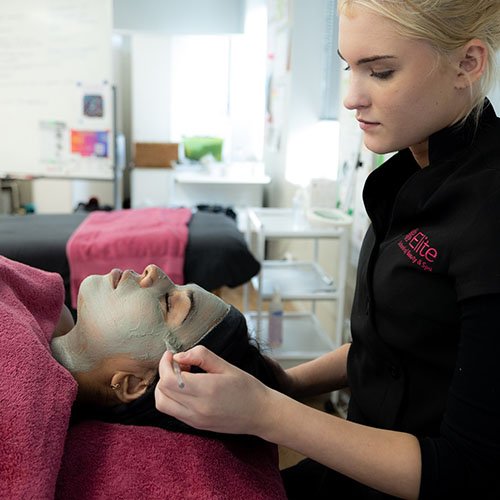 Elite student applies face mask for client.